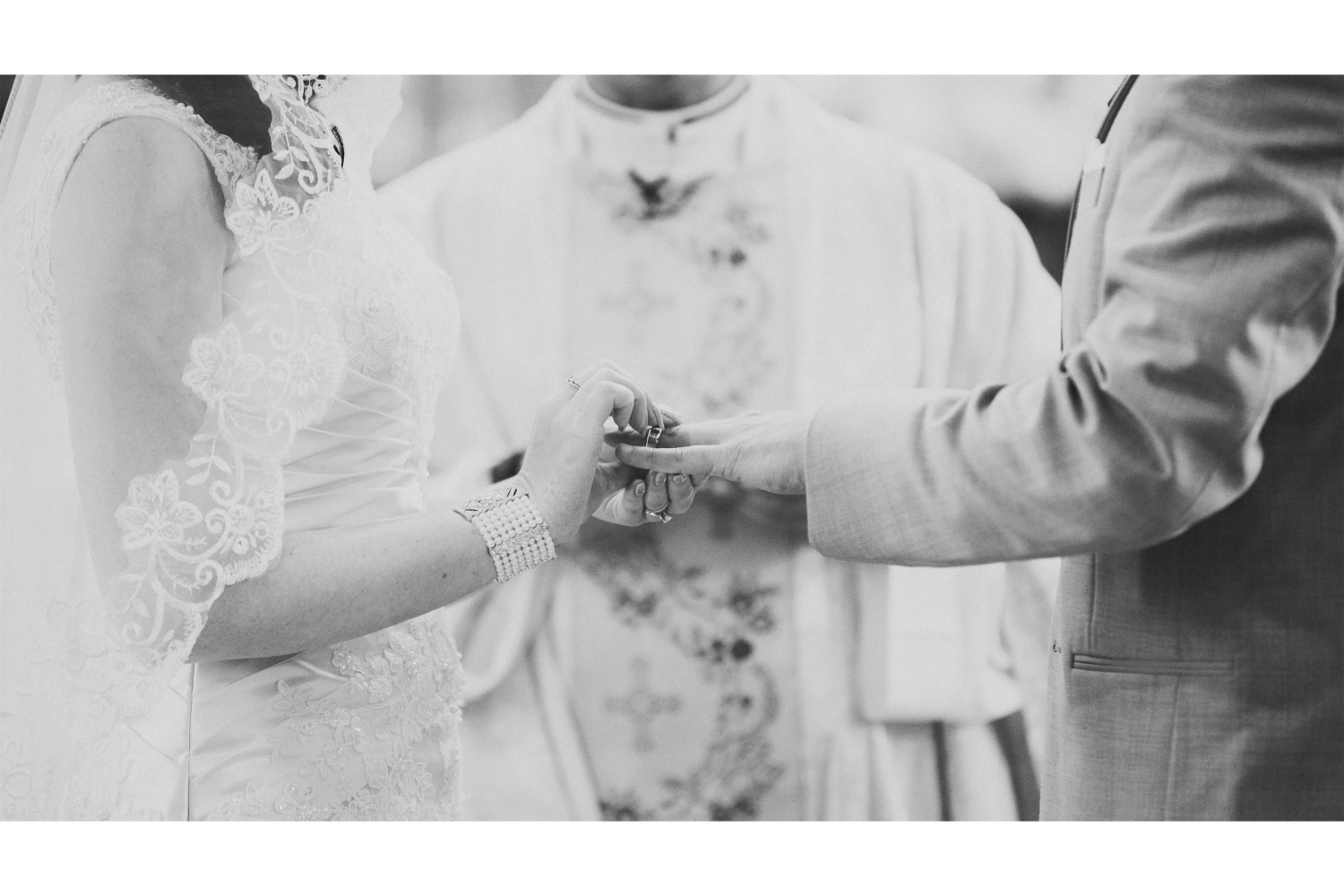Black and white photograph of the bride and groom exchanging rings during their wedding ceremony.