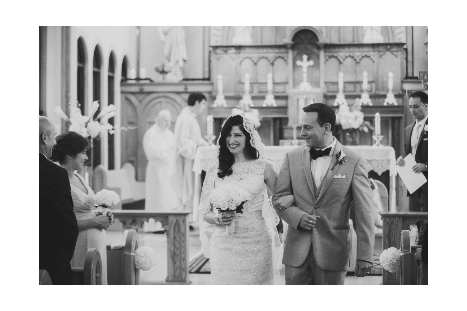 Black and white portrait of the bride and groom smiling during their wedding ceremony.