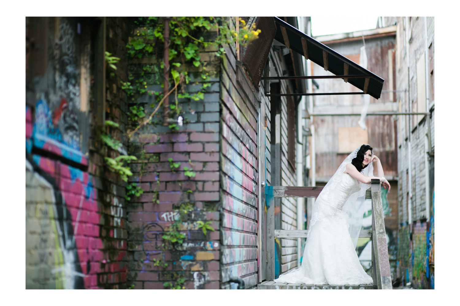 Bride posing against a backdrop of graffiti in East Vancouver during wedding portraits.