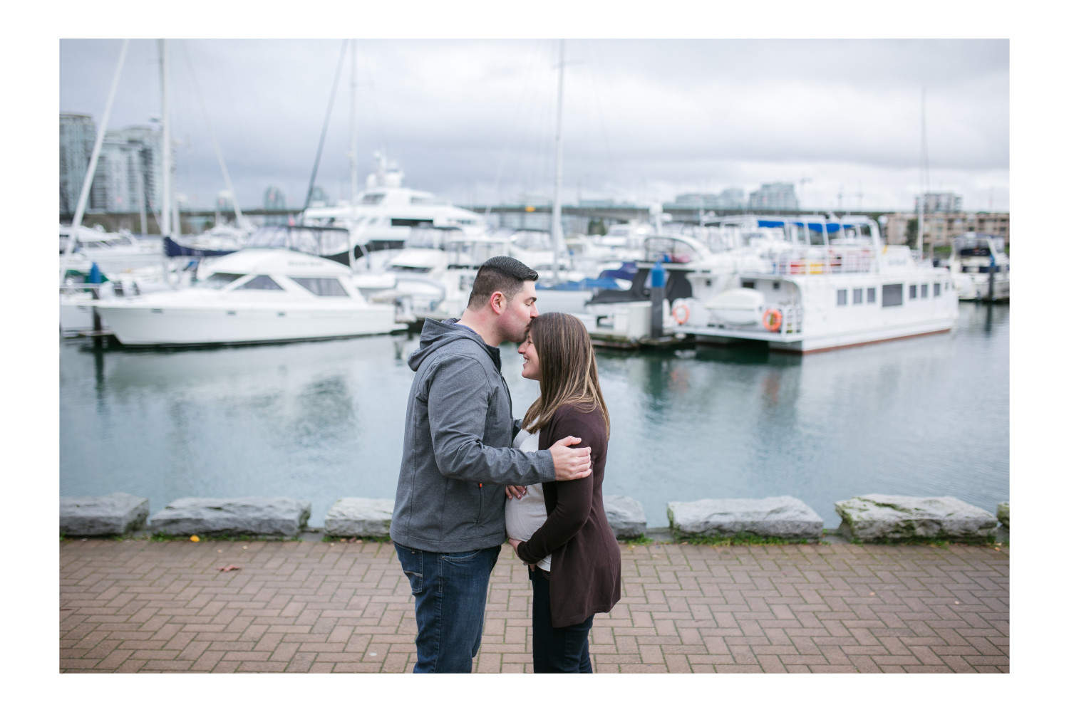 Couple kissing beside water during Vancouver maternity session.