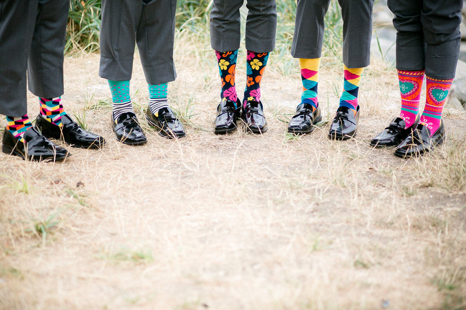 Groomsmen showing colourful socks during bridal party photos at English Bay in Vancouver, Bc.